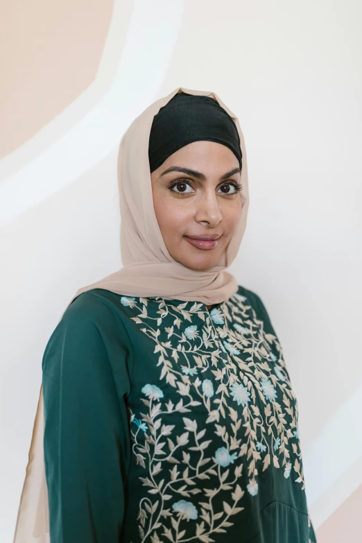 a woman standing with head scarf on wearing a green outfit