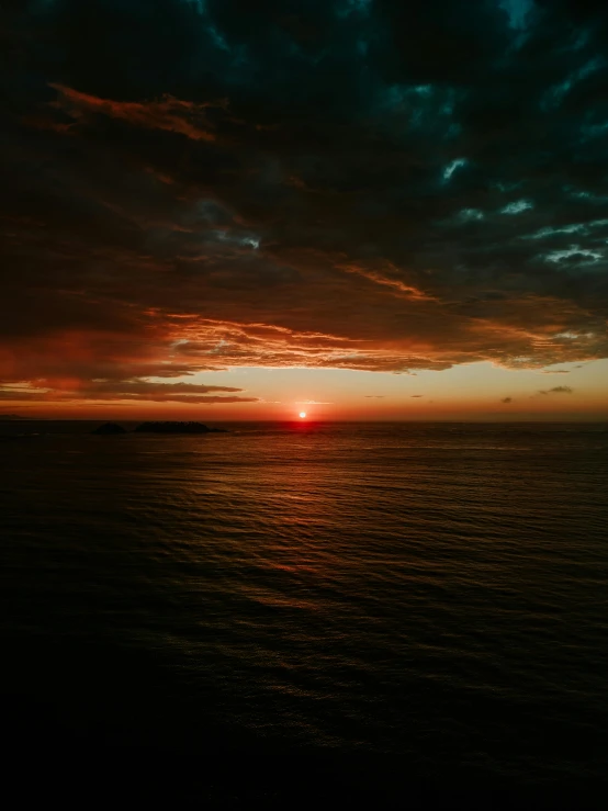 a very beautiful sunset over the ocean with a boat in the foreground