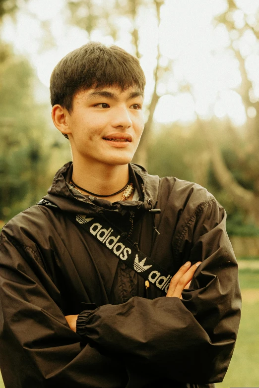 a boy is standing in the park wearing a hoodie