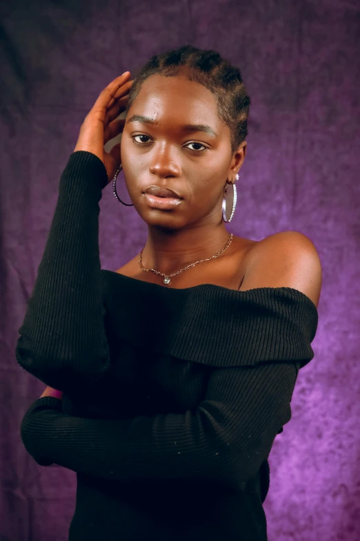 a girl poses in a black dress, against a purple background