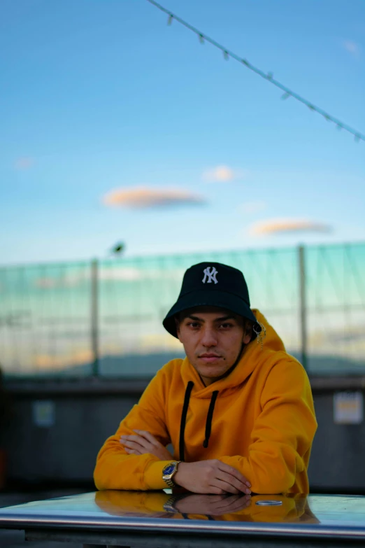 a man wearing a yellow jacket and a hat sitting at the top of a car