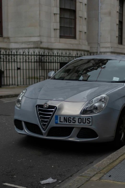 a silver car parked at a curb next to a fence