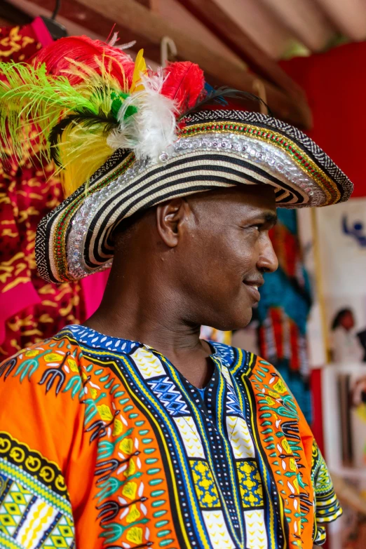 a man wearing a brightly colored headdress stands in front of other items