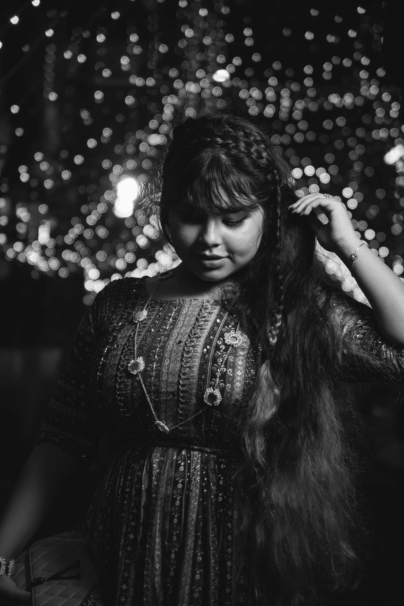 black and white pograph of woman holding her hair in front of the night sky