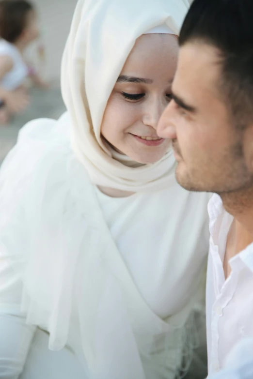 a woman wearing a headscarf looks at her husband