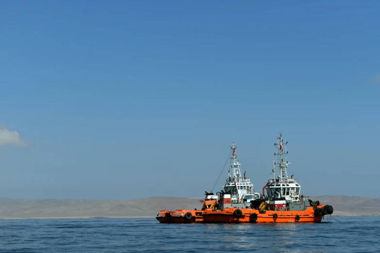 a couple of orange boats floating on top of a large body of water