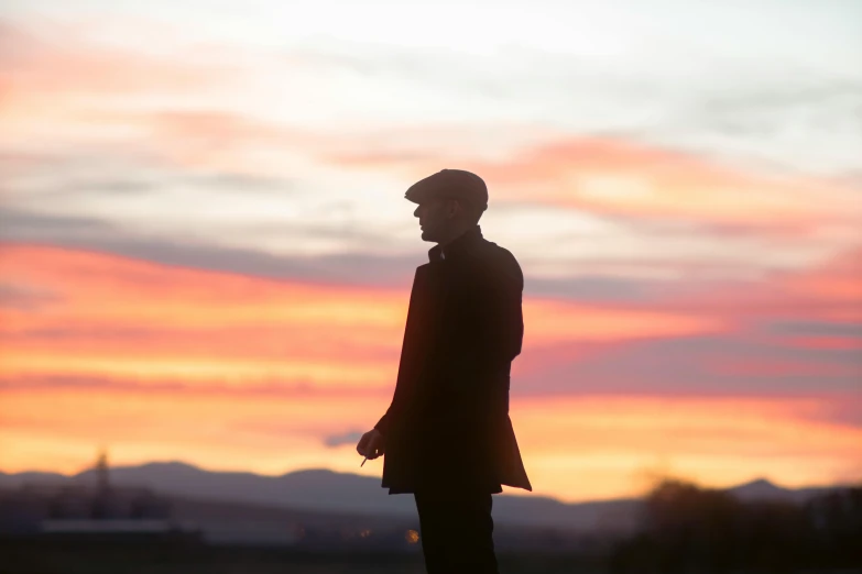 a silhouette of a man standing next to the sunset