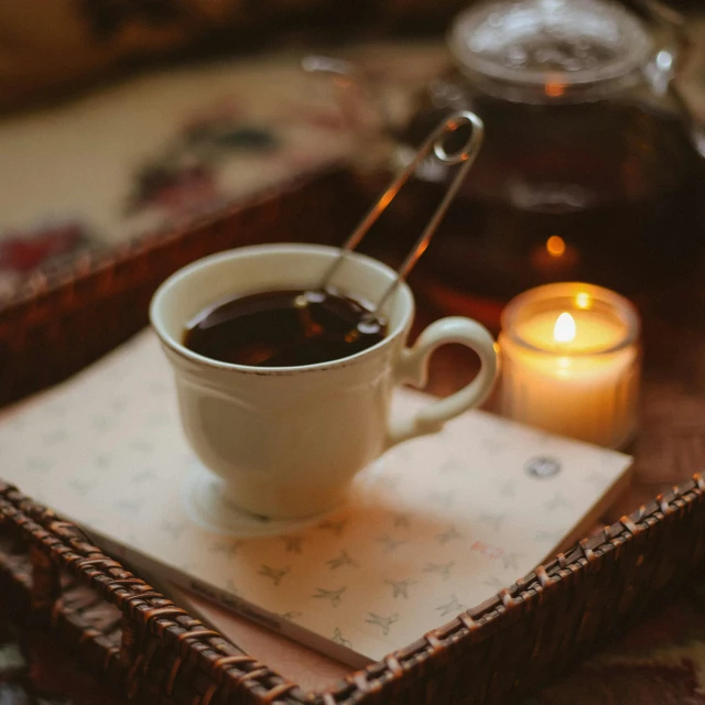 a cup of coffee sitting on a coaster near a tealight