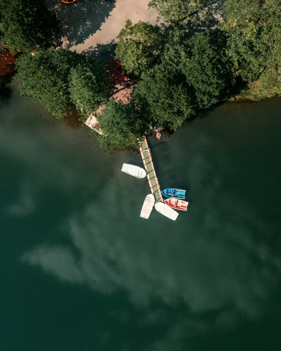 an aerial view of boats docked in the water next to a wooded area