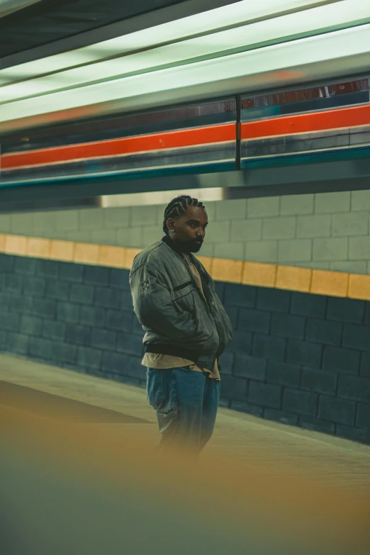 man stands alone at subway station looking down