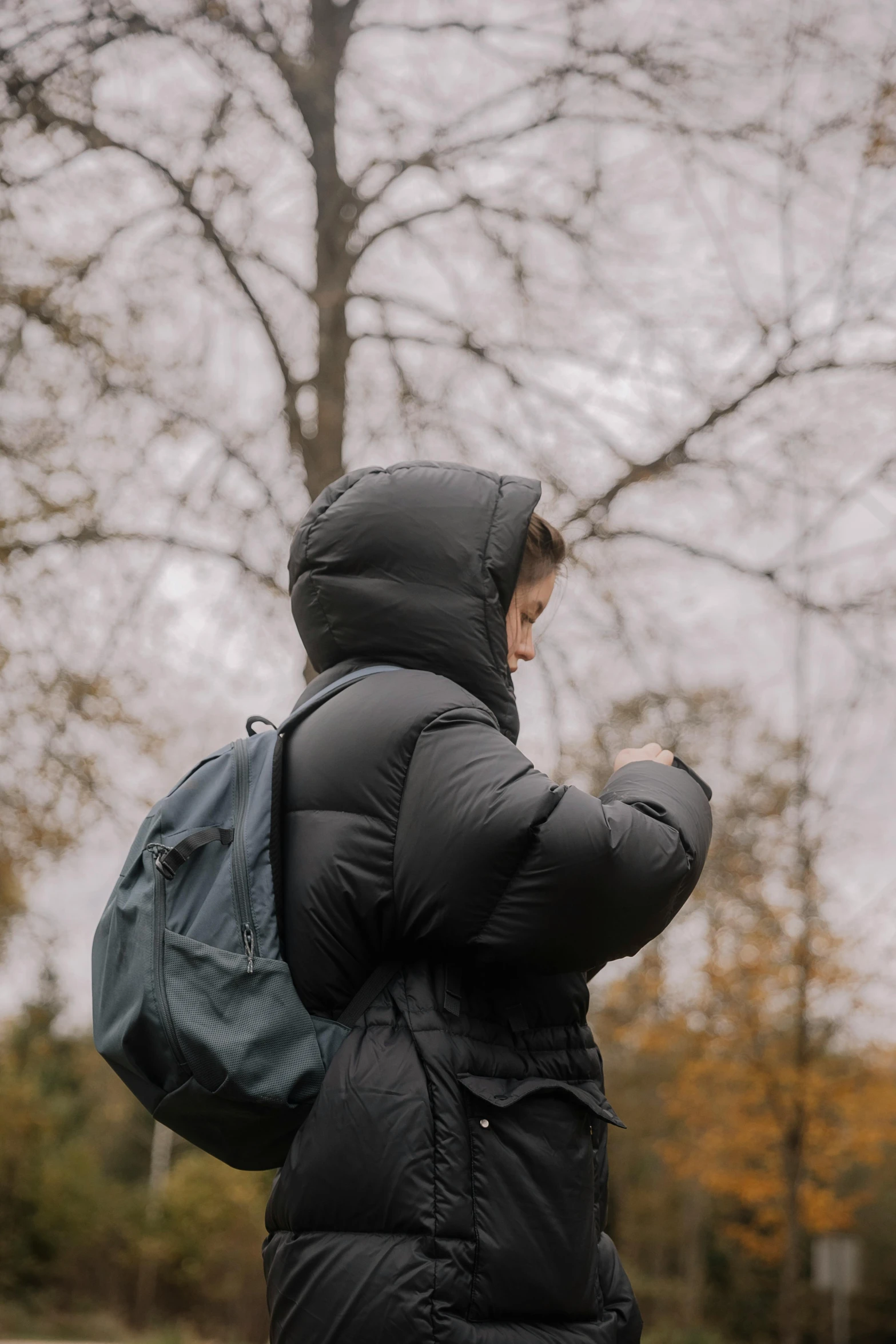 a woman in winter clothing and holding a book bag