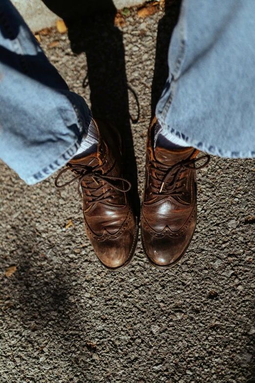 a person is standing wearing some brown shoes