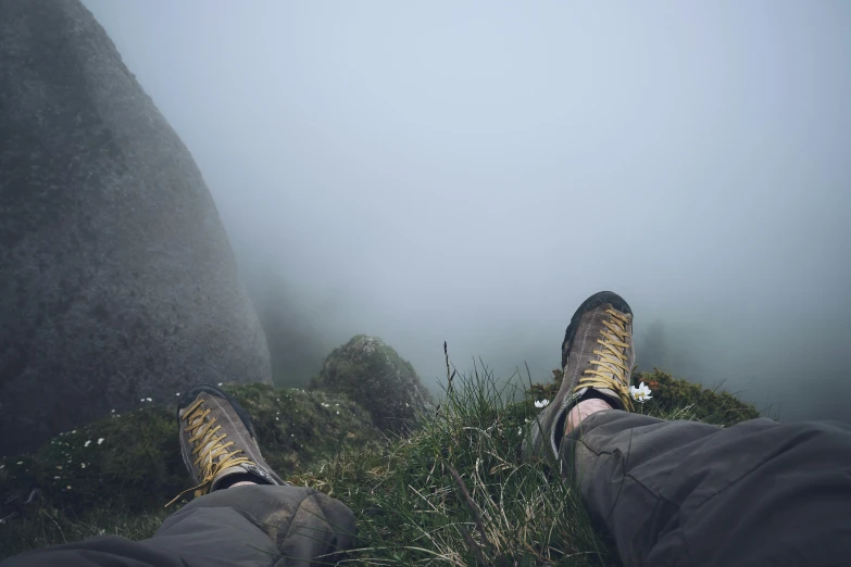 two feet are shown on the ground with a mountain in the background