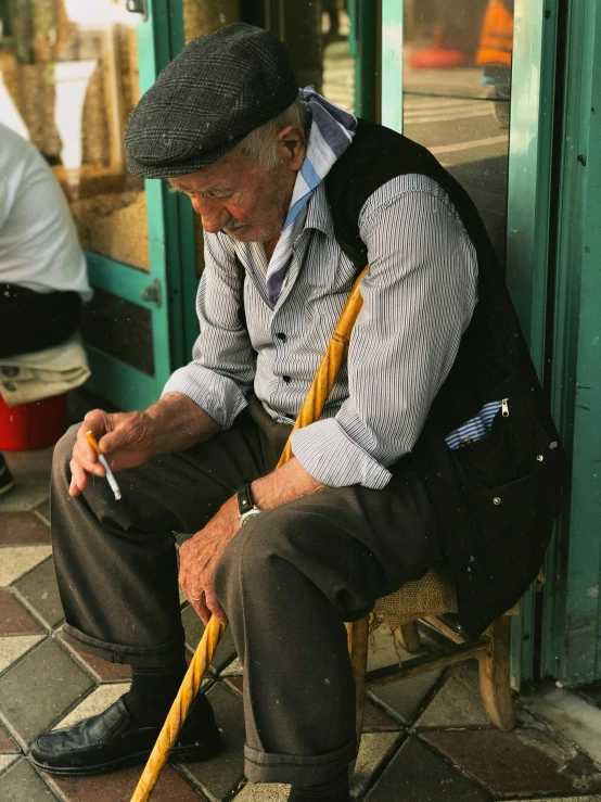 an older man sits outside with a cigarette in his hand