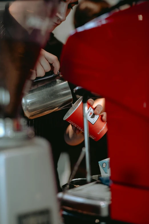 red coffee cups being filled with liquid from espresso machines