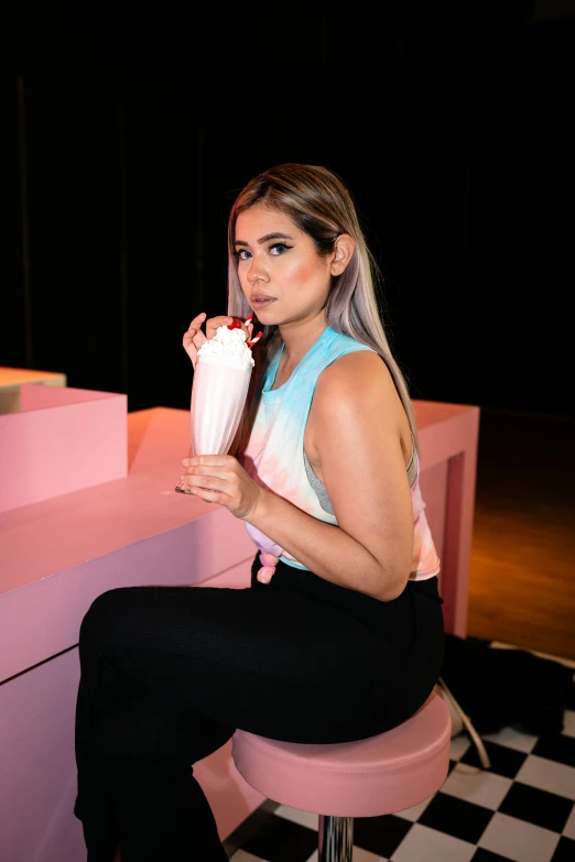 a woman sitting on a stool with a drink in her hand