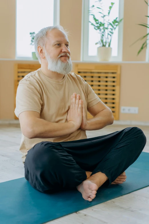 a man sitting in a yoga position on a mat