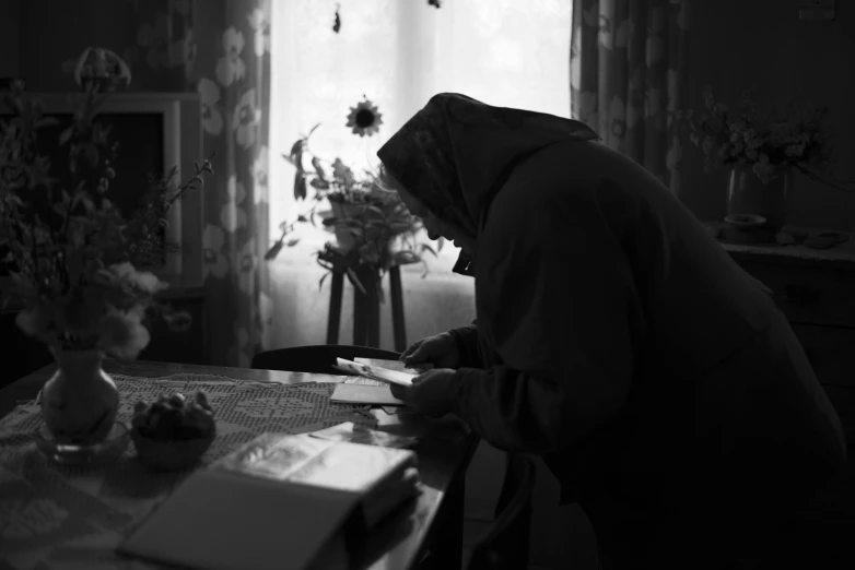 a person in hijab sitting at a table near a vase