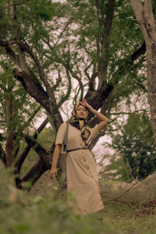 a lady in a scarf standing near a tree