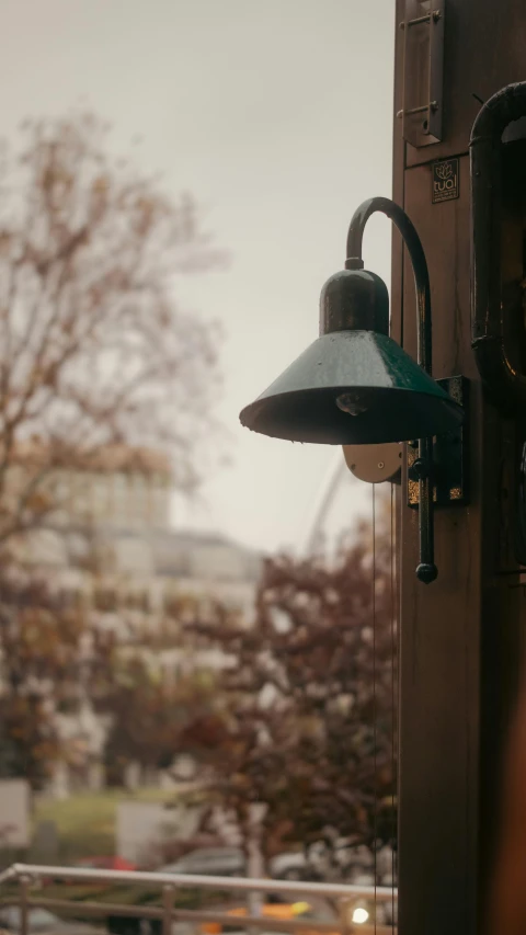 a small metal light with a green light is hanging from a wall