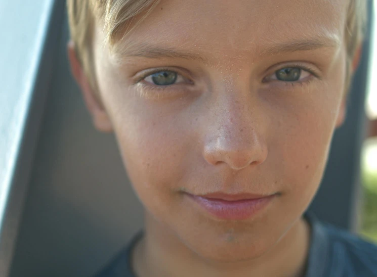 a little blond boy with blonde hair posing for the camera