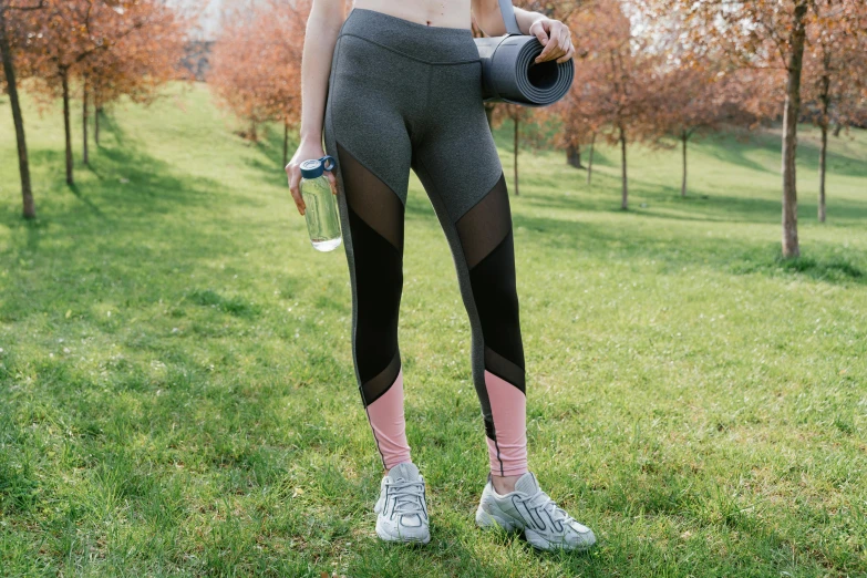 a woman in sports clothing is holding a bottle