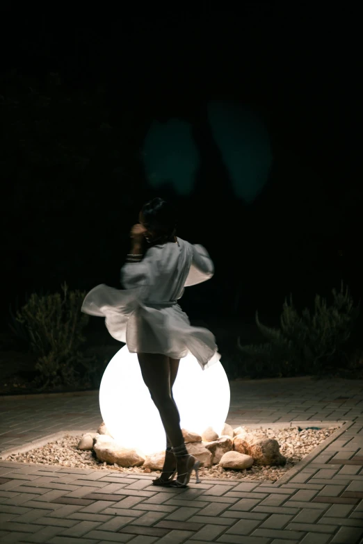 the woman is dancing in her dress by the light