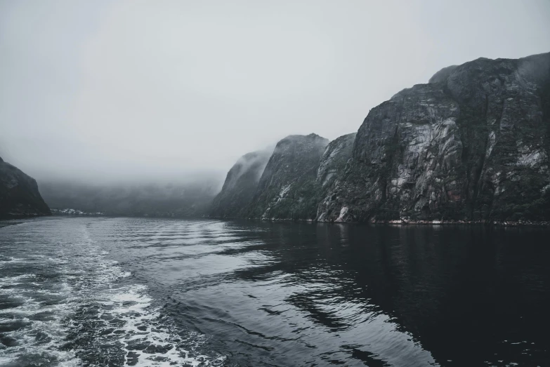foggy mountain with dark water and rocky cliffs