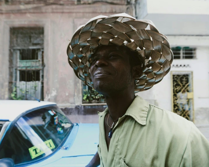 man in hat stands next to an old car