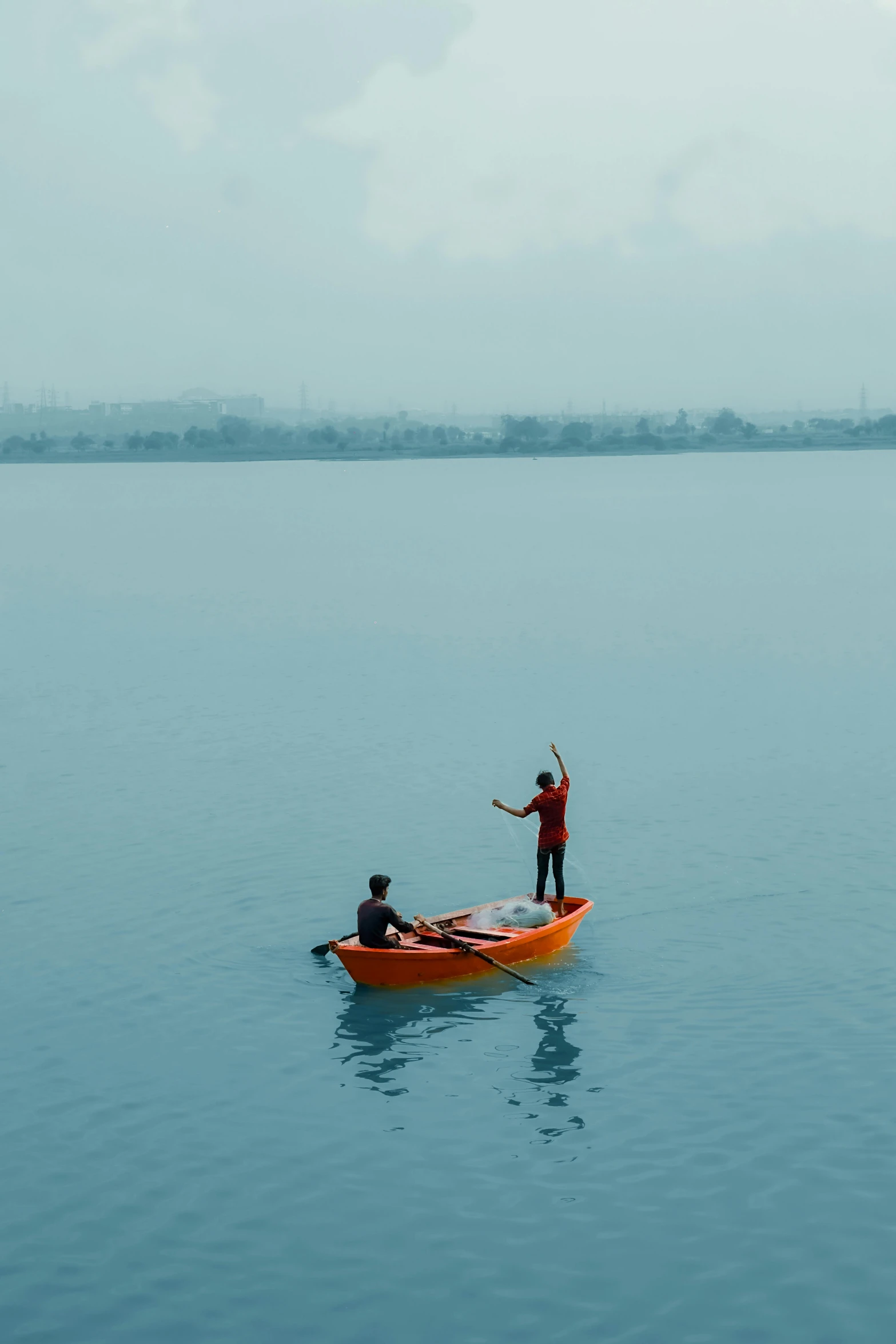 a man in an orange kayak paddles across calm blue water