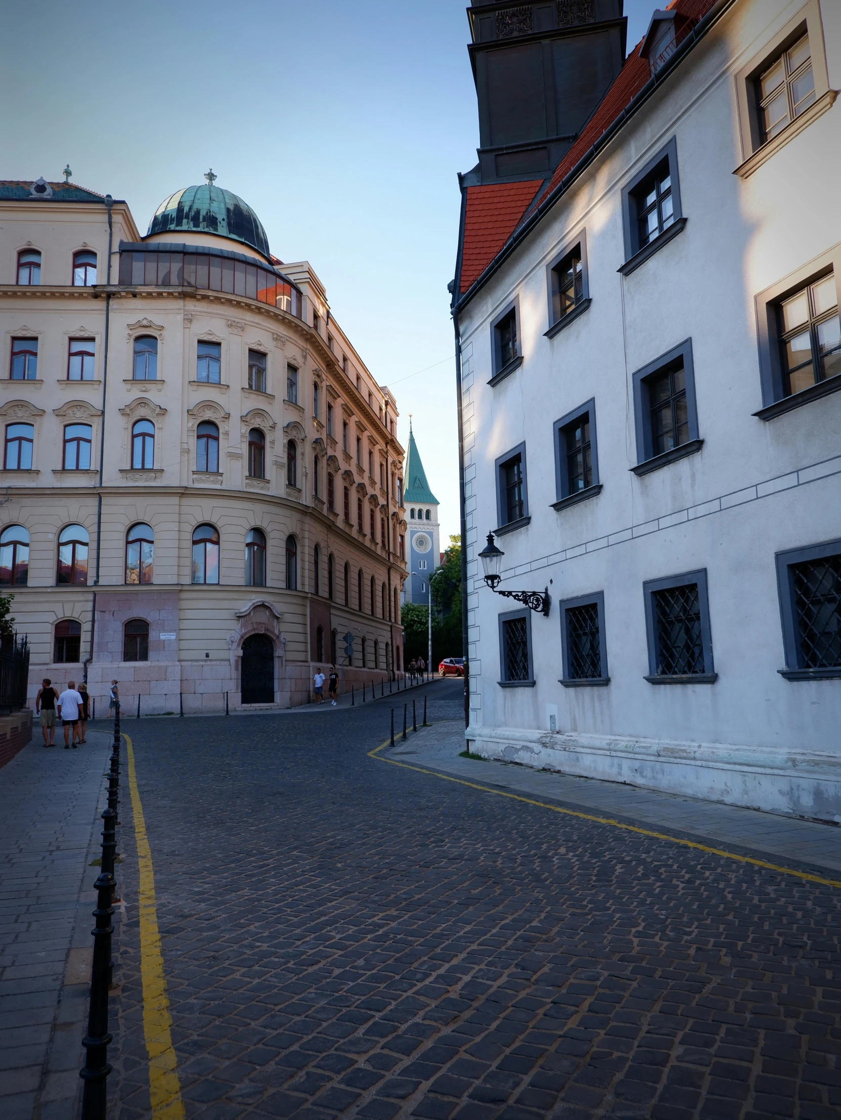 a paved cobblestone street with buildings and a clock tower on top