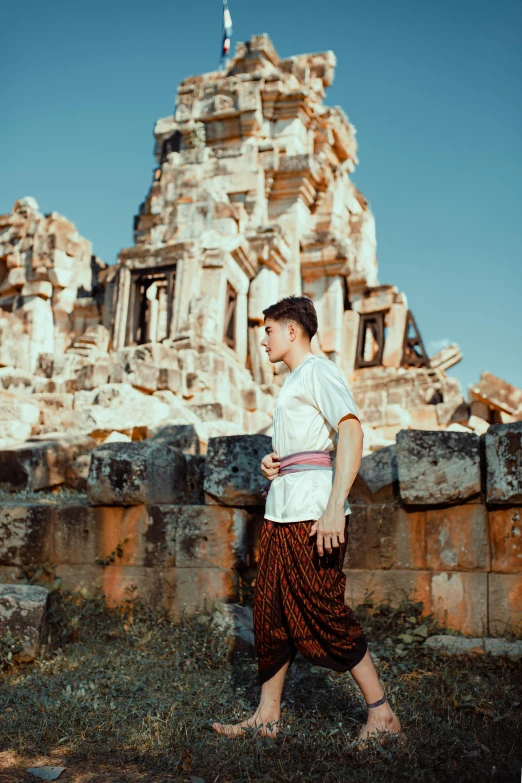 a young man walks past a crumbling building