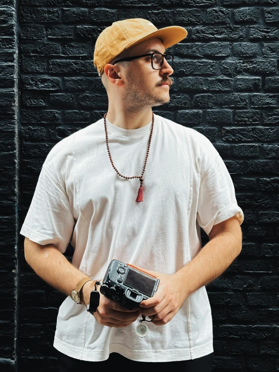 a man in a baseball cap and glasses holds a camera
