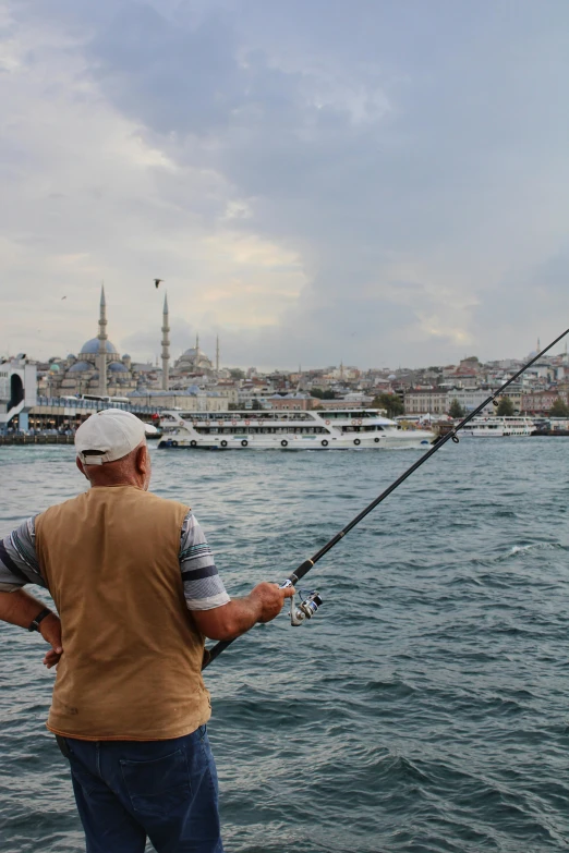 two men on the water fishing with a city in the background