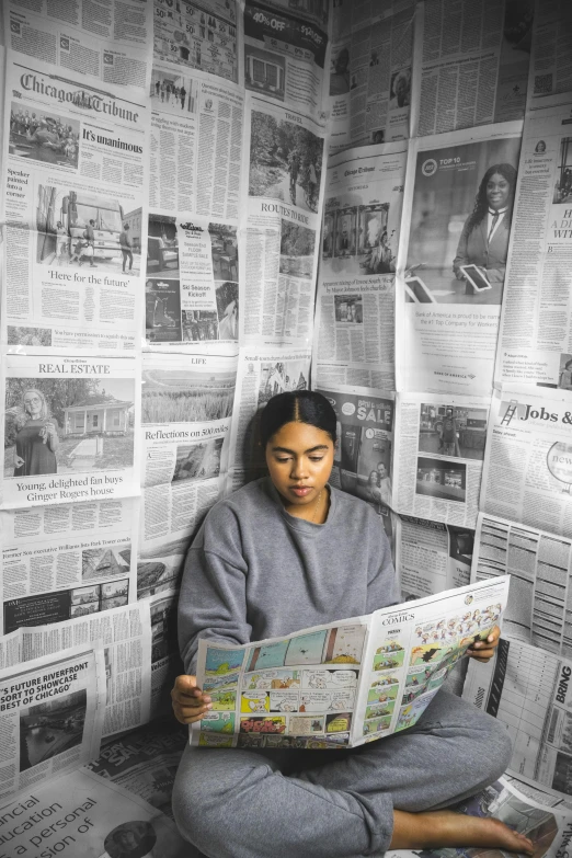 woman in pajamas sitting on the floor reading a newspaper