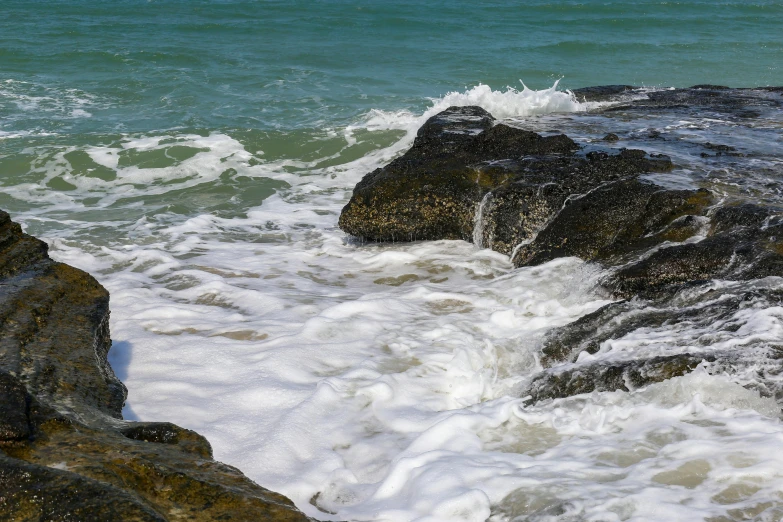 two rocks near the water, with the ocean waves crashing in