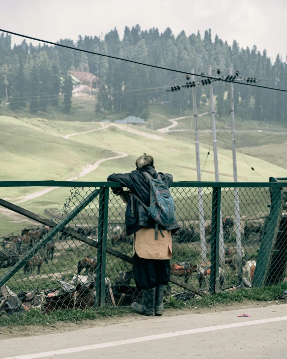 a man standing near the fence next to the road