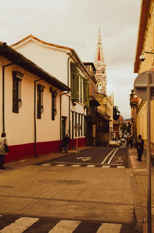 a street with buildings in the background and a woman sitting on a bench