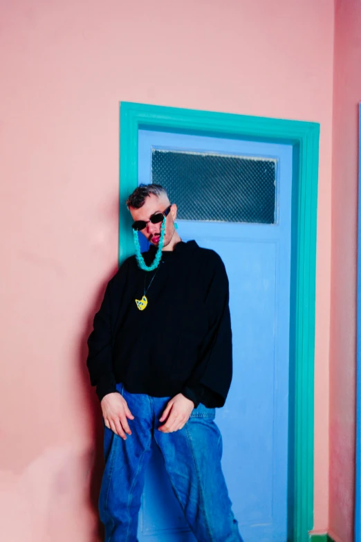 a man standing by a door wearing a black sweater