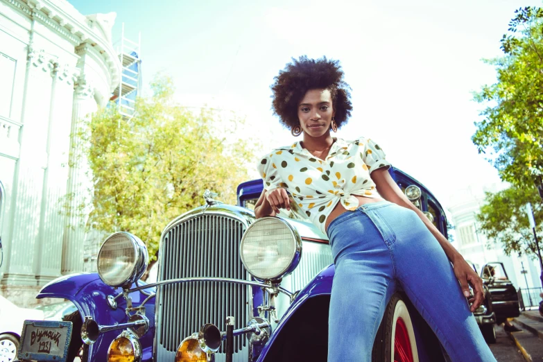 the woman is sitting on top of an old style car