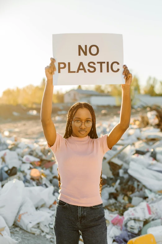 a girl holding up a sign in a garbage pile