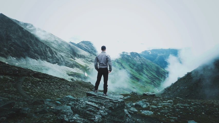 man standing in the clouds on top of a mountain