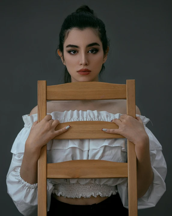 a woman in a white blouse holds up a chair