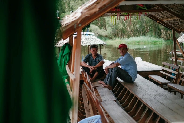 two men sitting on a boat looking off into the distance