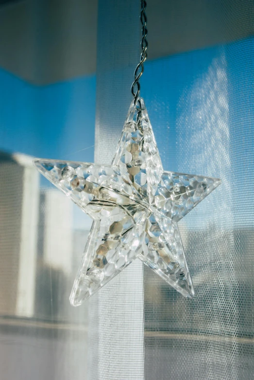 a clear star shaped piece hanging from a window