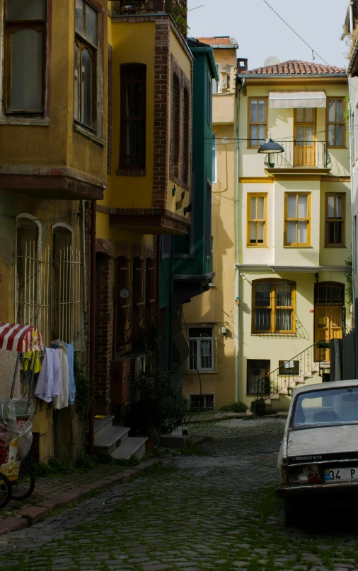 an old fashioned car parked in the middle of a cobblestone street