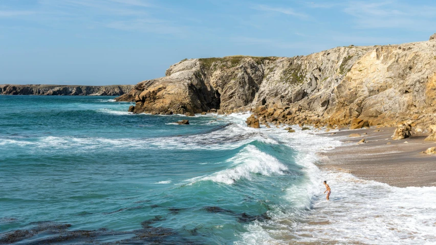 some people walking on the shore by the ocean