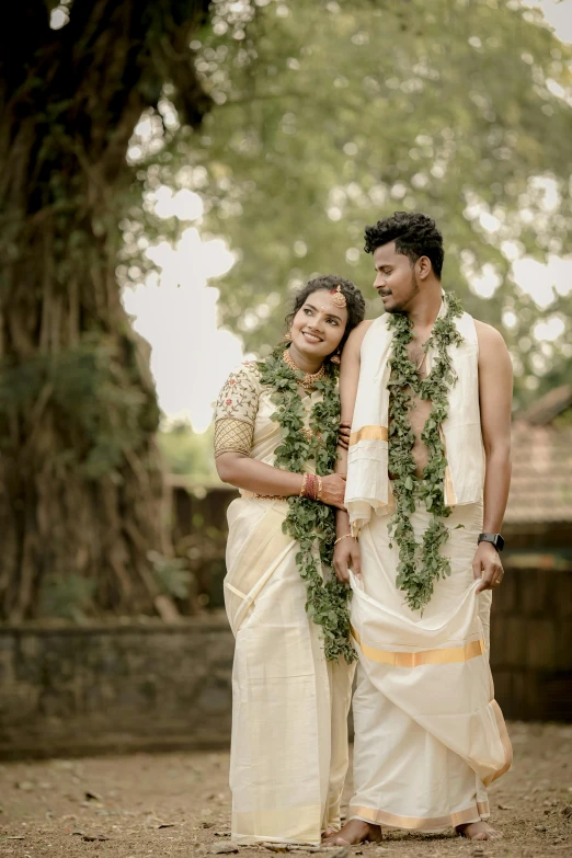 couple dressed in traditional wear in front of tree