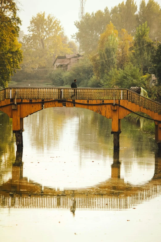 a couple stands on the wooden bridge in the rain