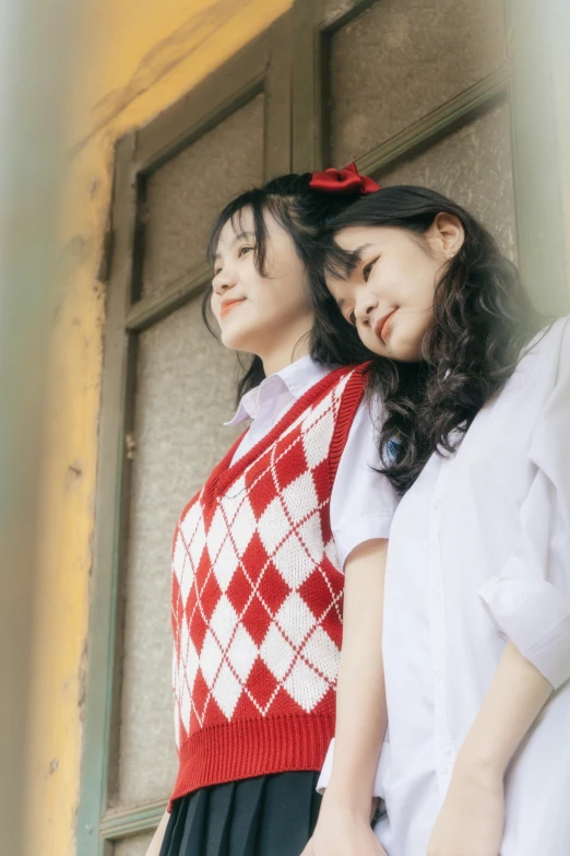 two women stand side by side, one in red and white